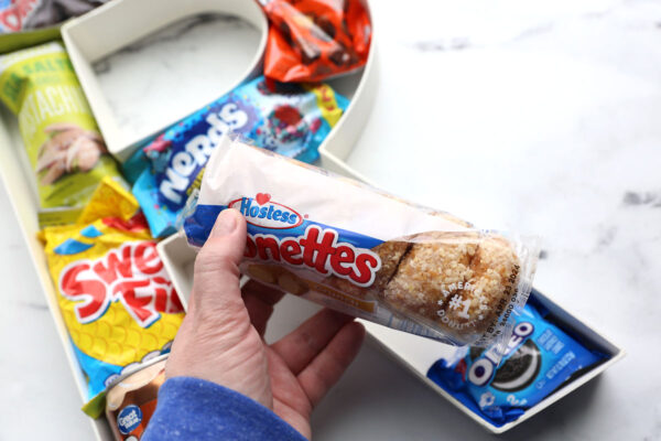 Placing treat with tape on it into the cardboard letter.