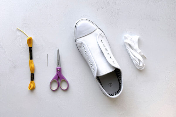Embroidery thread, small scissors, canvas shoe with laces removed.