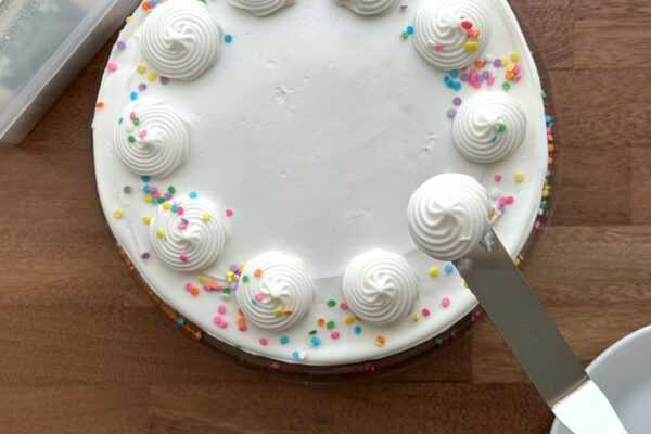 Removing extra frosting from cake.