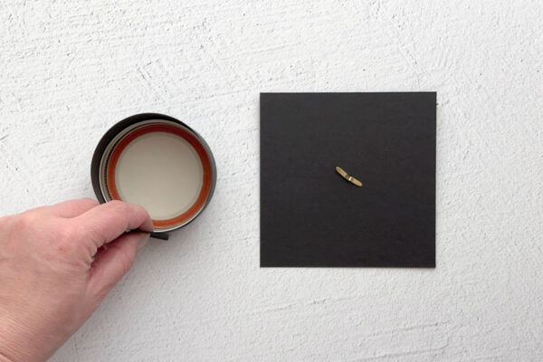 Wrapping the rectangle of cardstock around the lid; brad pushed through center of cardstock square.