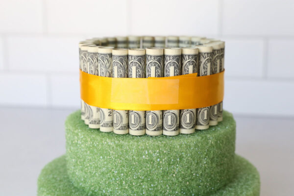 Top tier surrounded in dollar bills and secured with ribbon.