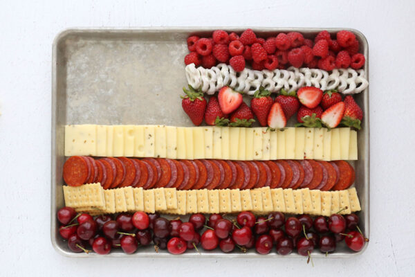 Top right of cookie sheet filled with strawberries, white chocolate pretzels, raspberries.