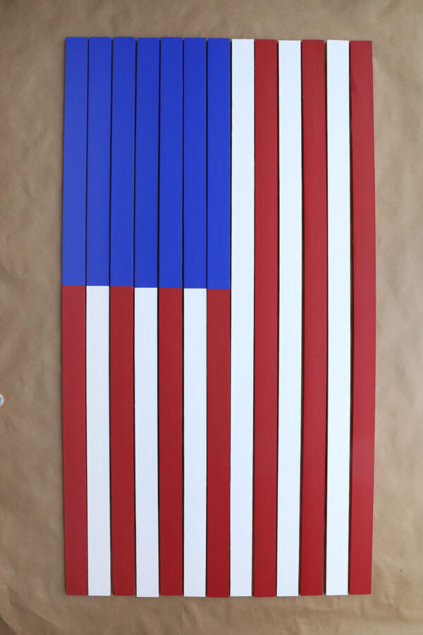 Yardsticks put together to make vertical flag, with blue at the top left.