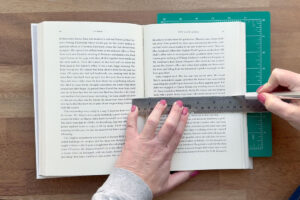 Measuring halfway up the book and cutting with exacto knife.