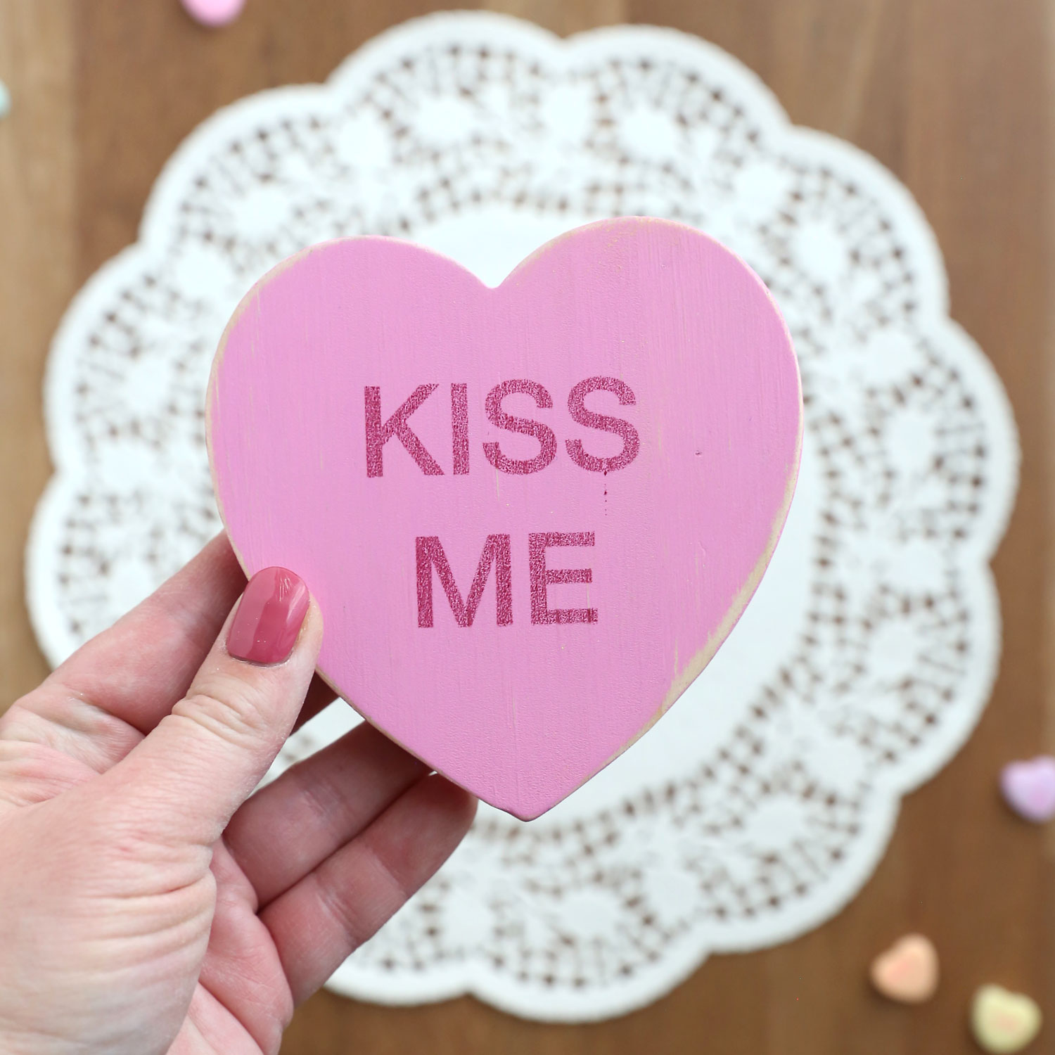 Hand holding a wooden conversation heart.