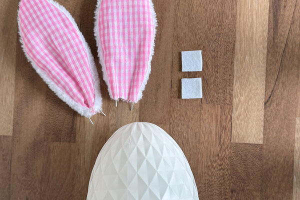 Smallest egg, bunny ears, two squares of white felt.