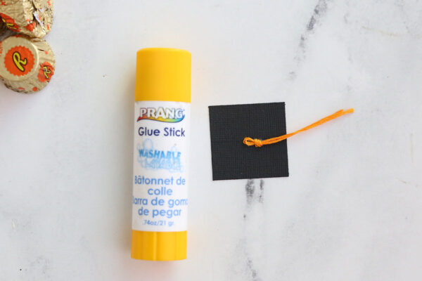 Use gluestick to glue tassel on top of black square.