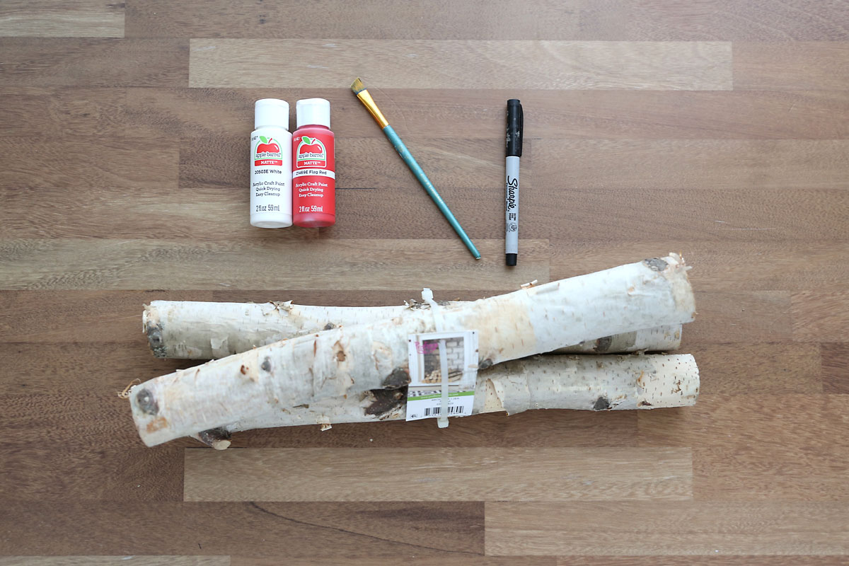 White paint, red paint, small paintbrush, Sharpie, birch logs.