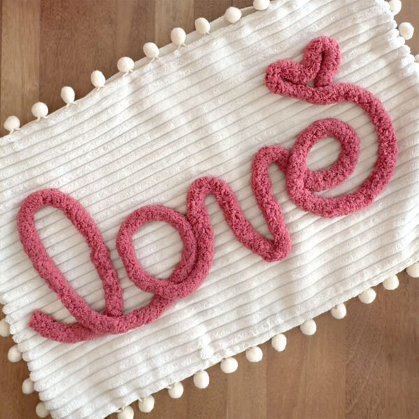 Yarn in shape of a word on the pillow cover.