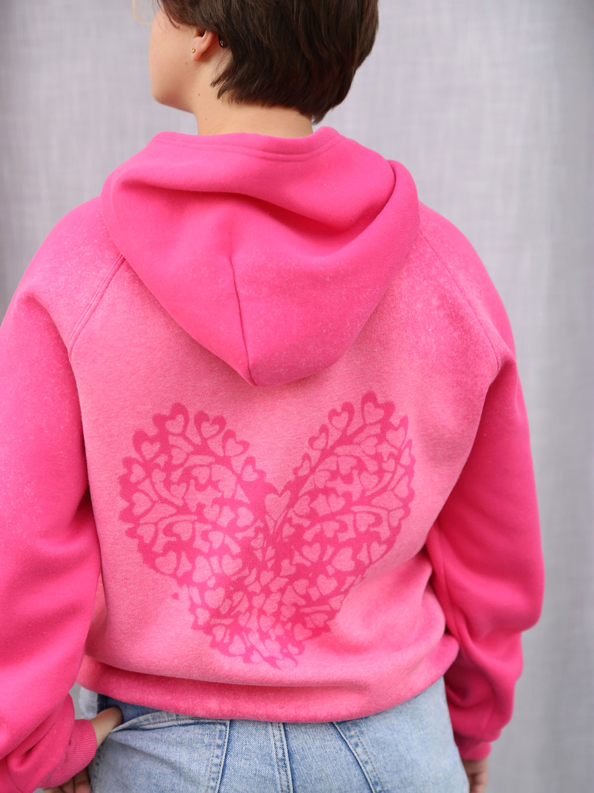 Girl wearing sweatshirt with bleach dyed heart on back.