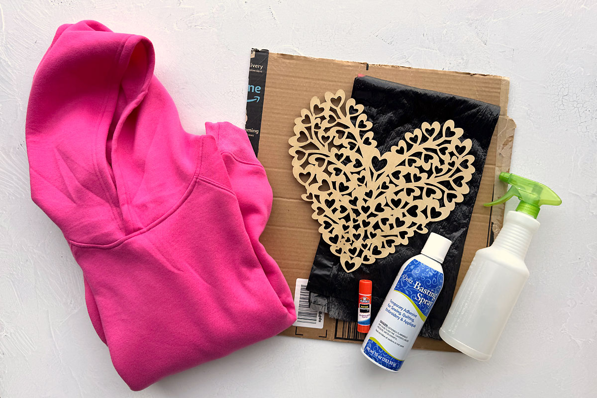 Hoodie, cardboard, black trash bag, wood heart cutout, glue stick, basing spray, spray bottle.