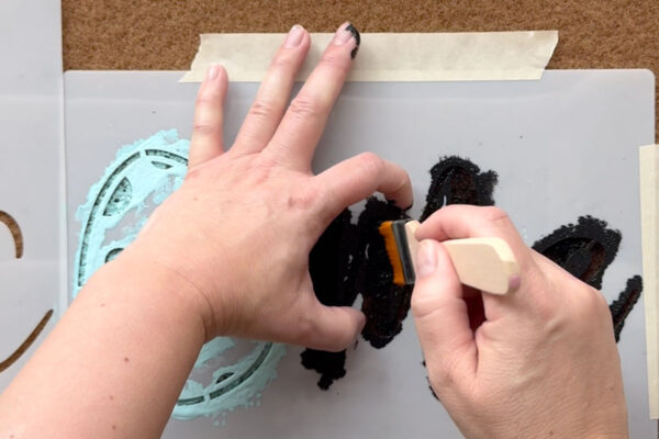 Painting on the stencil, holding the stencil down.