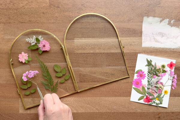 Using tweezers to place flowers on frame.