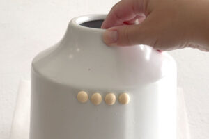Split wood balls glued onto vase in a row.