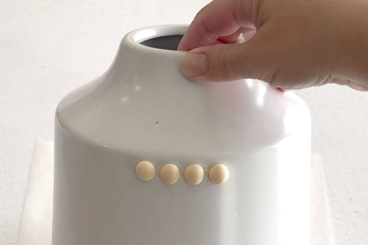 Split wood balls glued onto vase in a row.