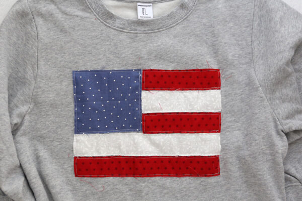 Sweatshirt with all stripes and blue square sewn onto sweatshirt.