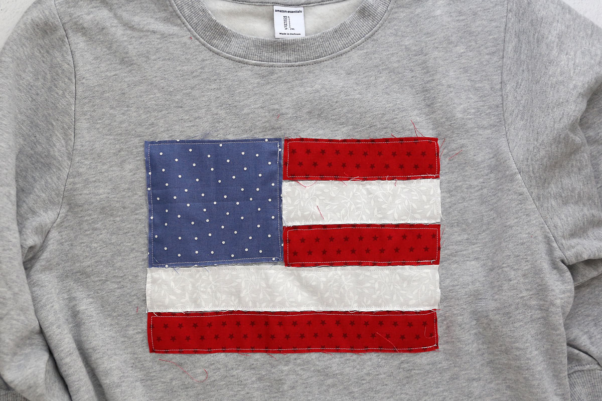 Sweatshirt with all stripes and blue square sewn onto sweatshirt.