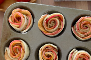 Unbaked apple roses in cupcake tin.