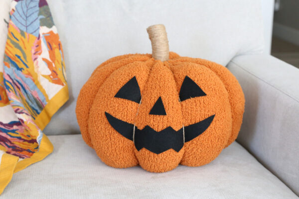 Jack-o-lantern pillow on a couch.